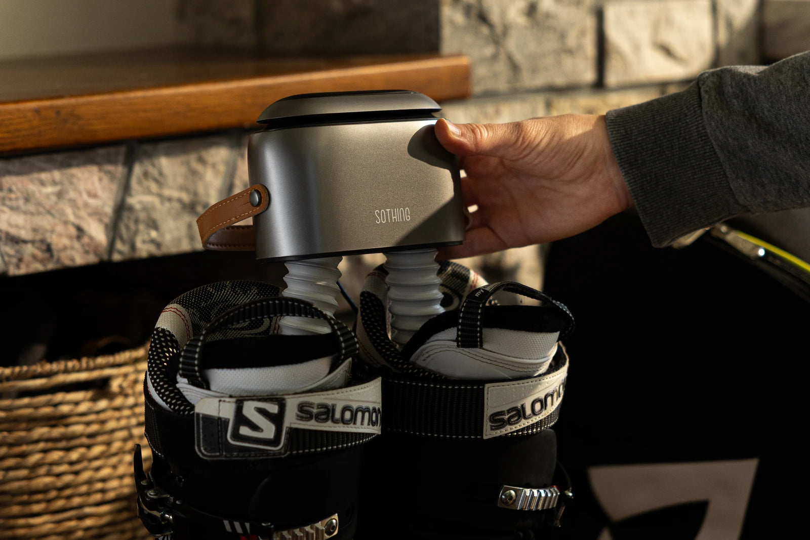 Original photograph of a hand holding the Ultra Grey above ski boots